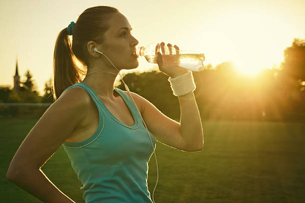 istock Woman drinking water at sunset after run 181754114