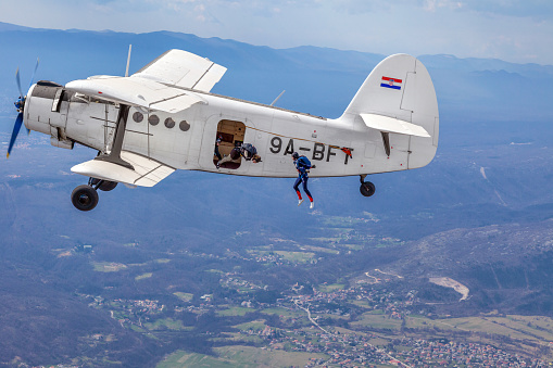 Rijeka, Croatia - March 28, 2010: Paratroopers jump out of an old military biplane