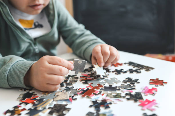 mãos de uma criança fazendo um quebra-cabeça na mesa - solution silver problems puzzle - fotografias e filmes do acervo