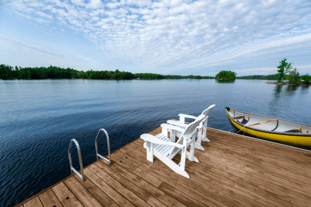 Dock chairs, calm lake, yellow canoe, peaceful sky. stock photo