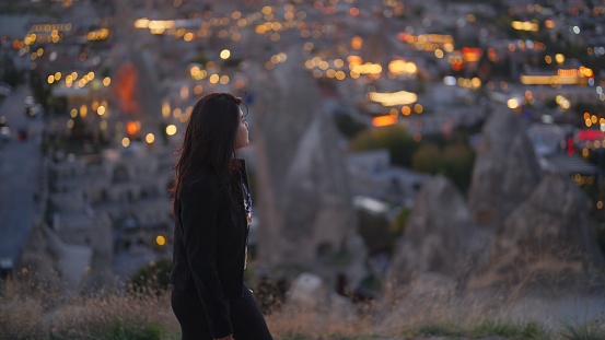 A portrait of a multiracial woman watching the sunset on top of a hill in Cappadocia in Türkiye Turkey.