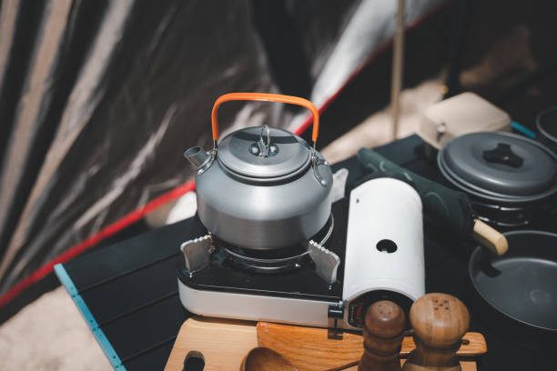 istock Prepare your campsite feast with this complete set, kettle, pot, pan, gas stove, flashlight, and camera, arranged by the tent at the beach. Camping in style and comfort. 1817752261