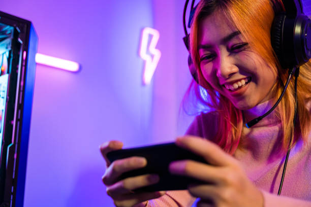 istock Happy Gamer playing video game online with smartphone with neon lights 1817752311