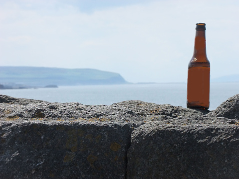 Bottle on a wall with the sea in the background editors text copy wording