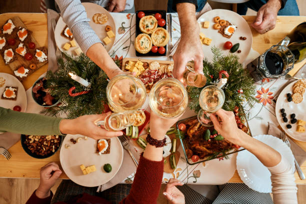 celebrating Christmas with the family New Year's Eve party, the big family dinner top view of a Christmas New Year's Eve decorated table, five non-personalized people eating at the table, passing dishes to each other big family table stock pictures, royalty-free photos & images