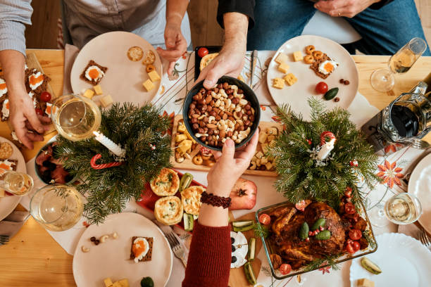 celebrating Christmas with the family New Year's Eve party, the big family dinner top view of a Christmas New Year's Eve decorated table, one person passes a plate of nuts to another person big family table stock pictures, royalty-free photos & images