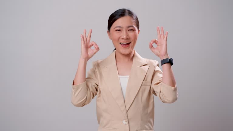 Asian woman happy confident showing OK sign by hand standing isolated over white background.