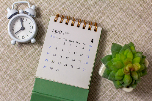 Desk calendar for April 2024 and a clock on the table.