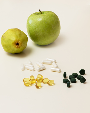 Concept for dietetics - still life with apple, pear, tablets and capsules