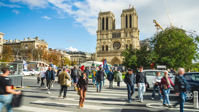 Time lapse Crowd of People tourist walking crossing road and sightseeing attraction at Notre-Dame Cathedral landmark still reconstruction in summer in Paris, France