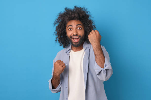istock Young overjoyed Arabian man waves arms triumphantly stands in studio 1817940212