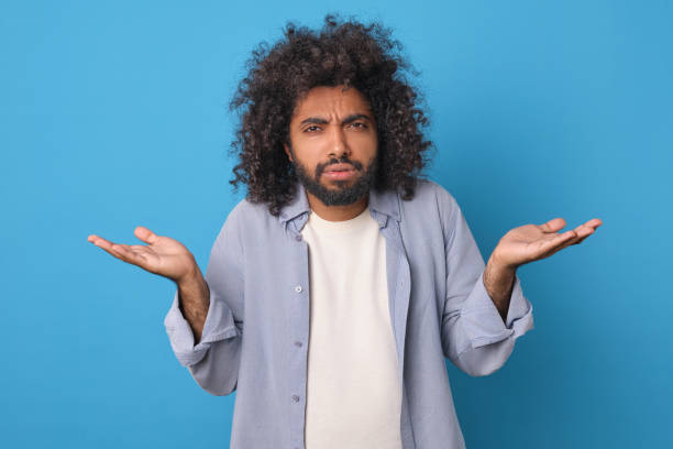istock Young embarrassed curly Arabian man throws up hands due to not knowing answer 1817943403