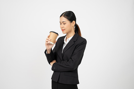 Young Asian businesswoman holding coffee cup and standing with white isolate background.