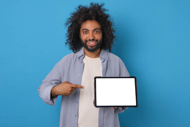 istock Young Arabian man holds electronic tablet and points finger at green display 1817949759