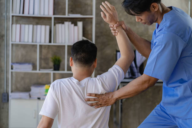 介護者と理学療法を行うアジアの男性患者腕と肩の筋肉損傷を持つ男性を助け、サポートする魅力的な介護者 - shoulder pain physical injury human arm ストックフォトと画像