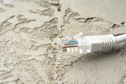 White network cable patch-cord on gray textured background close up