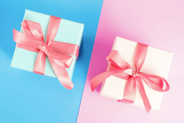 istock Three gift boxes with ribbons on pink and blue background close-up, top view. 1817981851