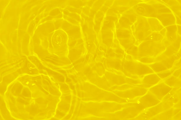 istock Yellow water with ripples on the surface. Defocus blurred transparent gold colored clear calm water surface texture with splashes and bubbles. Water waves with shining pattern texture background. 1817986034