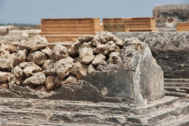This stock photo features the excavated architectural fragments and stone artifacts from the ancient Temple of Zeus in Euromos, displayed in the open-air museum area in Milas, Muğla. These pieces—column drums, capitals, friezes, and carved stone blocks—were uncovered during ongoing archaeological excavations at the Euromos site. Each artifact reflects the craftsmanship of the Hellenistic and Roman periods, offering insight into the temple’s original scale and architectural sophistication. The open-air arrangement allows visitors to observe the details of the ancient stones up close while appreciating the historical significance of one of Caria’s most important archaeological sites.