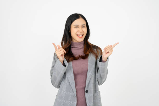 istock Young asian business woman, smiling while pointing finger, standing over white background. 1818001403