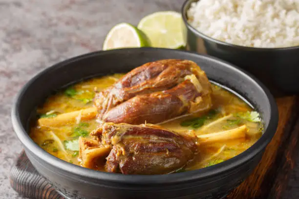 Nihari Pakistani lamb Shank Stew is a traditional slow-cooked one-pot meal made with meat in spicy gravy closeup on the wooden board on the table. Horizontal