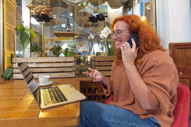 istock A young girl works at a cafe while on the phone and computer drinking coffee 1818018740