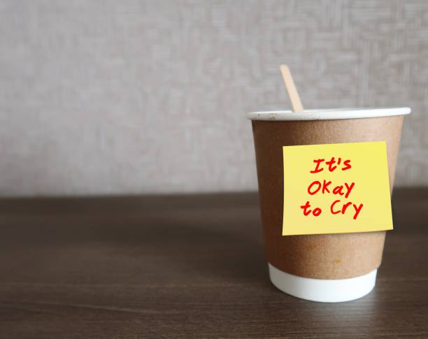 istock Coffee cup on copy space background with text written note  IT'S OKAY TO CRY - handle painful emotions with tears, is not weakness but willingness to let it out, good for mental health 1818026176