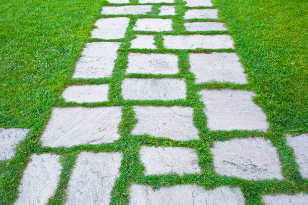 Old paving in a public park made with irregularly shaped stone blocks in a pedestrian zone and fresh green lawn