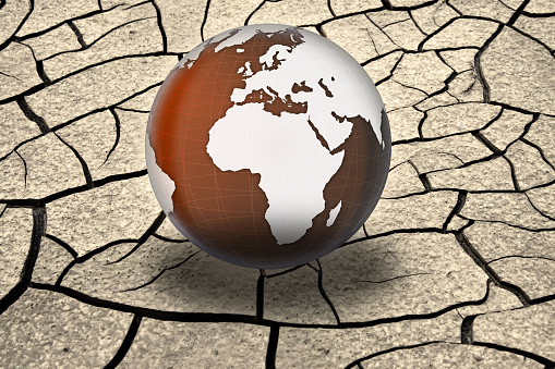 Planet Earth in the hot dunes of a beach. Conceptual image about global droughts as a result of climate change. \nVisual references from NASA (https://visibleearth.nasa.gov/images/74117/august-blue-marble-next-generation).