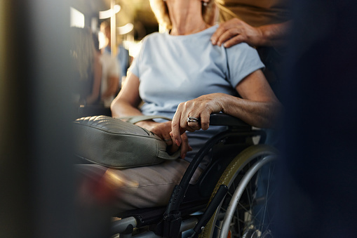 Close up of unrecognizable senior woman in a wheelchair traveling by a bus.