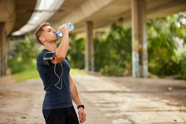 istock Male runner under bridge in the city drinking water 1818060154