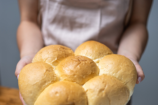 Female baker showing freshly baked bread buns close up