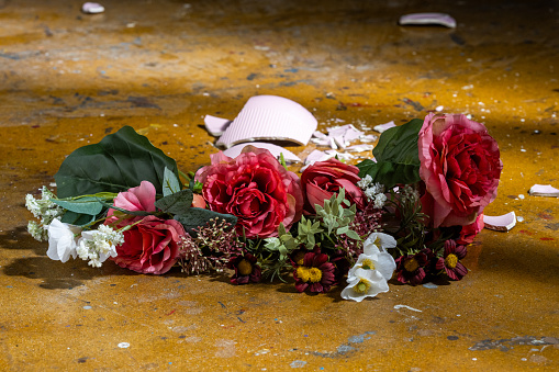 Broken vase with flower bouquet on dirty floor