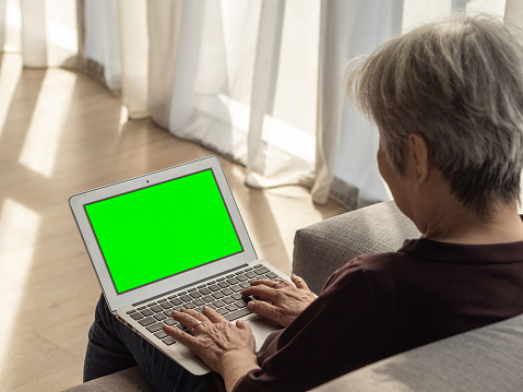 People - Portrait of a senior Asian Chinese woman using her laptop in living area (with green screen)