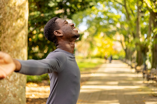 Man with arms open and eyes closed, breathing fresh.