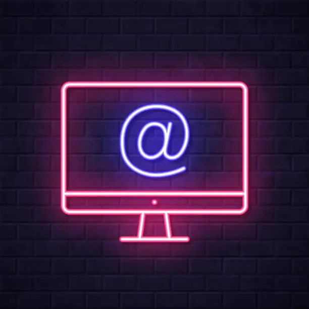 Vector illustration of Desktop computer with At symbol. Glowing neon icon on brick wall background