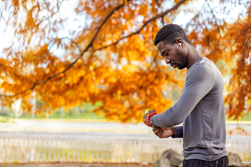 Male runner synchronizing wireless earphones with smart watch.
