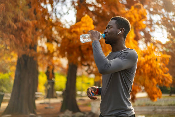 Overheated black guy drinking water from bottle in park
