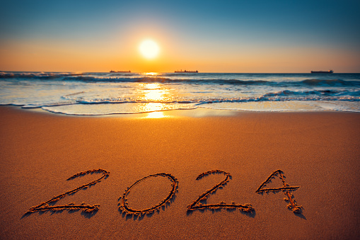 Happy New Year 2024 concept, lettering on the beach. Sea sunrise.
