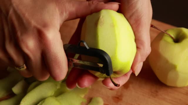 woman in the kitchen peels apples for apple cake