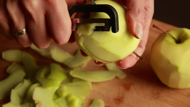 woman in the kitchen peels apples for apple cake