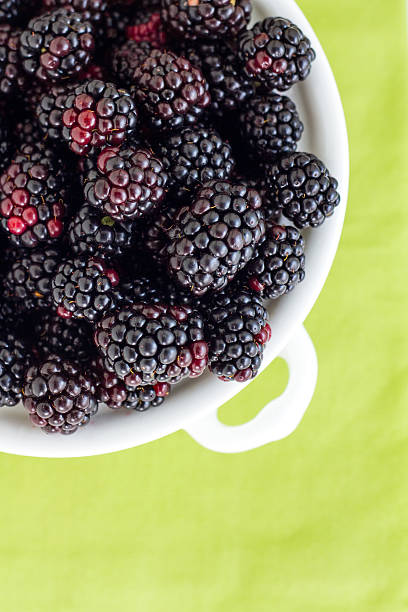 Blackberries on Green Part of a series showing the preparation of Apple and Blackberry Pie. marionberry stock pictures, royalty-free photos & images