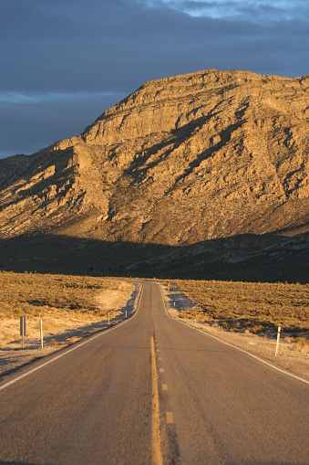 A late afternoon glow lights the way as the road heads towards an impending storm.