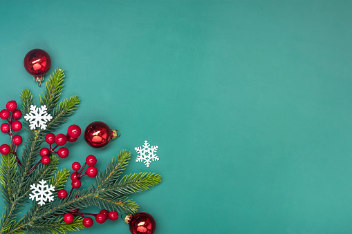 Christmas banner with green fir tree branches, mistletoe and red baubles decoration on white background. The composition is at the left of an horizontal frame leaving useful copy space for text and/or logo.