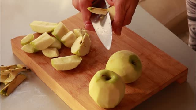 Female hands cut green apple in pieces. Close up
