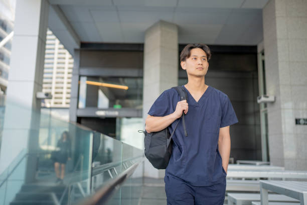 jovem enfermeiro caminhando por uma cidade - male nurse medical student healthcare and medicine nursing assistant - fotografias e filmes do acervo