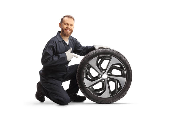 istock Car mechanic kneeling next to a tire and pointing 1818173546