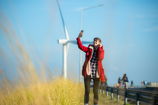On the background of windmills, A young woman in a red jacket is enjoying her winter vacation.