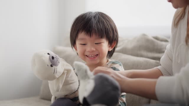 Cute small child sit playing puppets toys having fun.