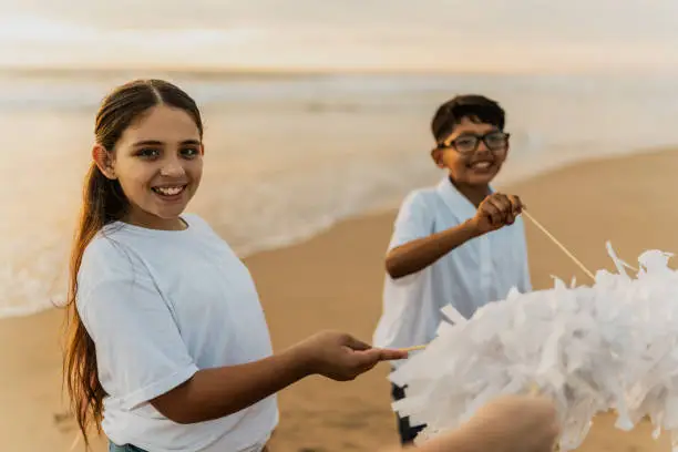 Photo of Portrait of a child girl playing pom pom with his friends on the beach